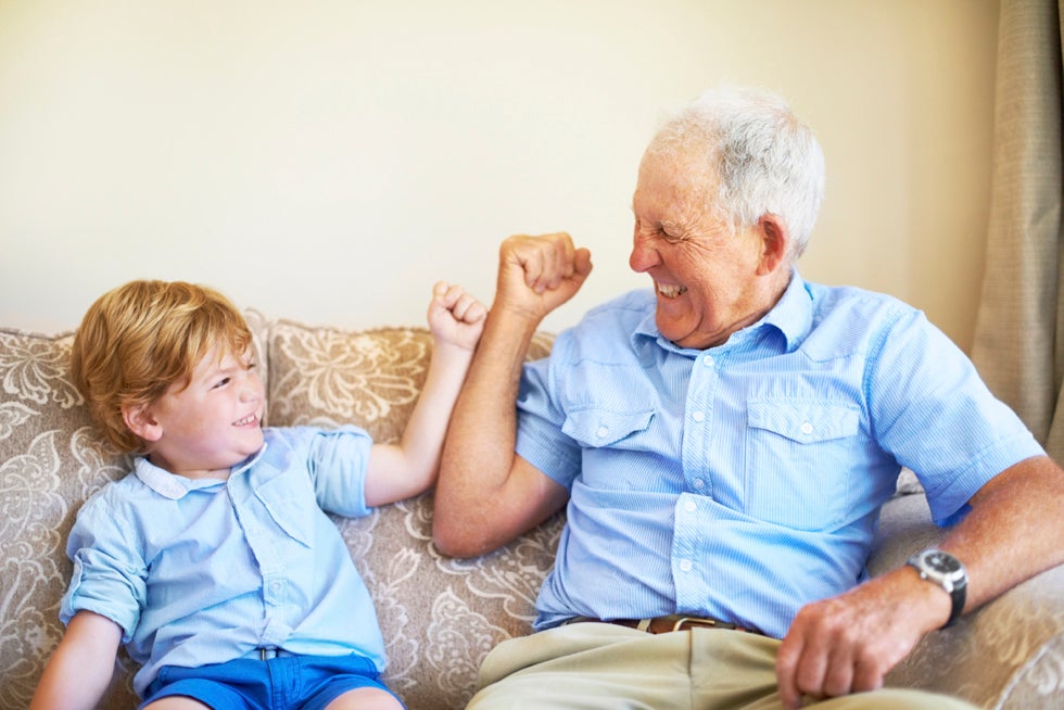 Grandfather and grandson relaxing and holding hands on the couch