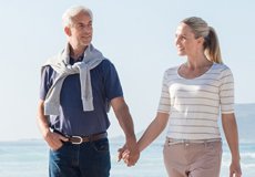 Couple holding hands while walking on the beach